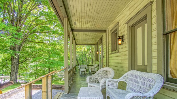 A covered porch with wicker furniture and a wooden railing. - 5 Br: Historic Glaab House in Cass, with AC, Amazing Kitchen, Covered Porches, Historical Landmark (Cass)
