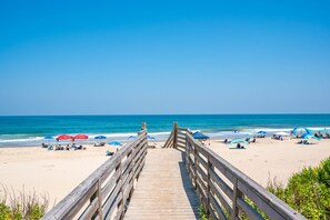 A wooden boardwalk leading to a beach with umbrellas and beach chairs. - The Purple Dandelion-Oceanside,dog-friendly 🐶easy beach access,community pool (Corolla)