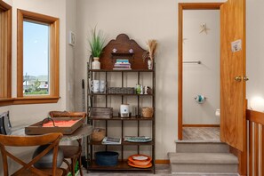 Un espace de vie compact comprenant une bibliothèque en bois, une petite table avec une chaise et une vue par la fenêtre.