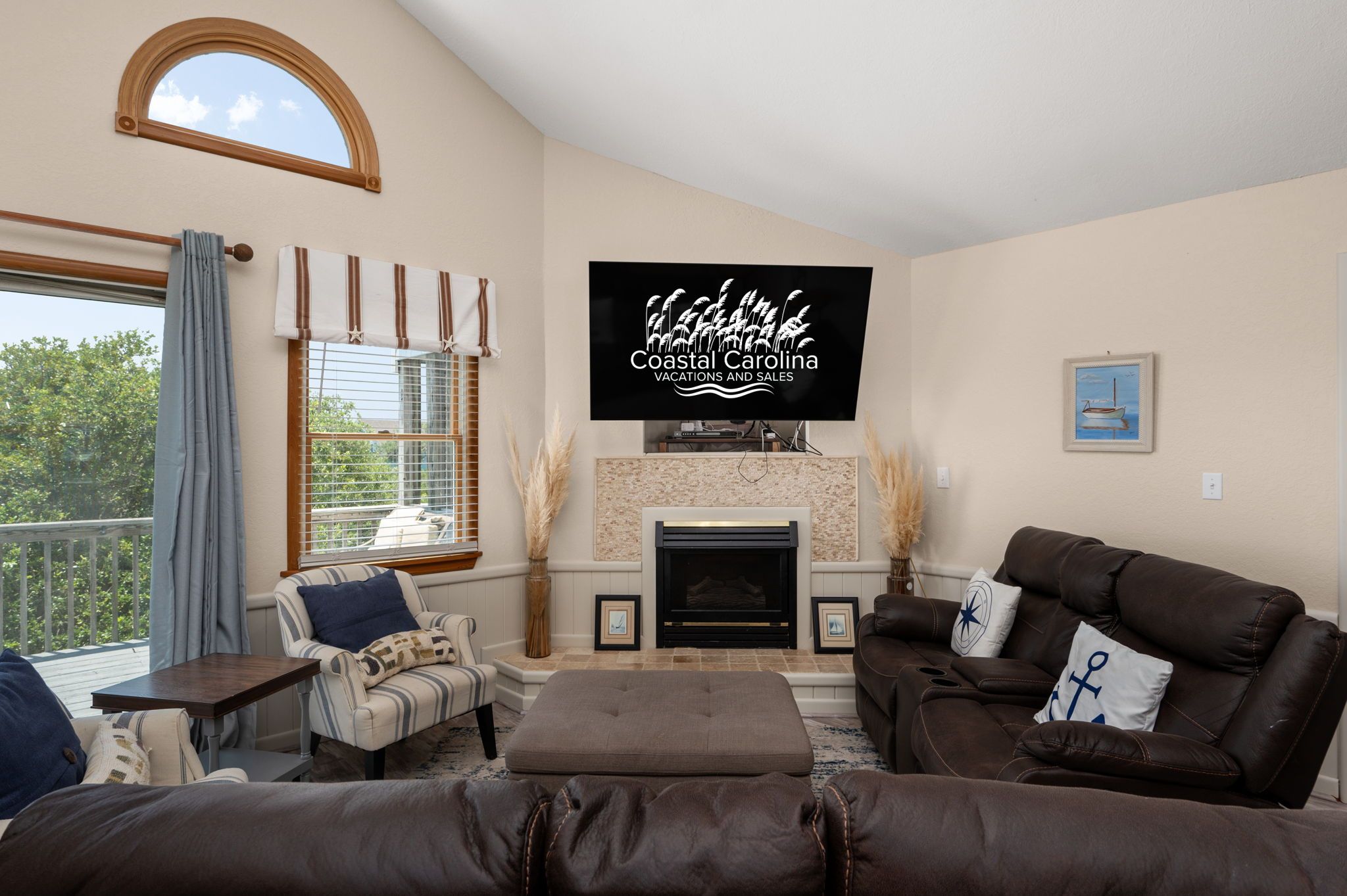 A living room with a fireplace, a television mounted above it, and a large window with curtains.