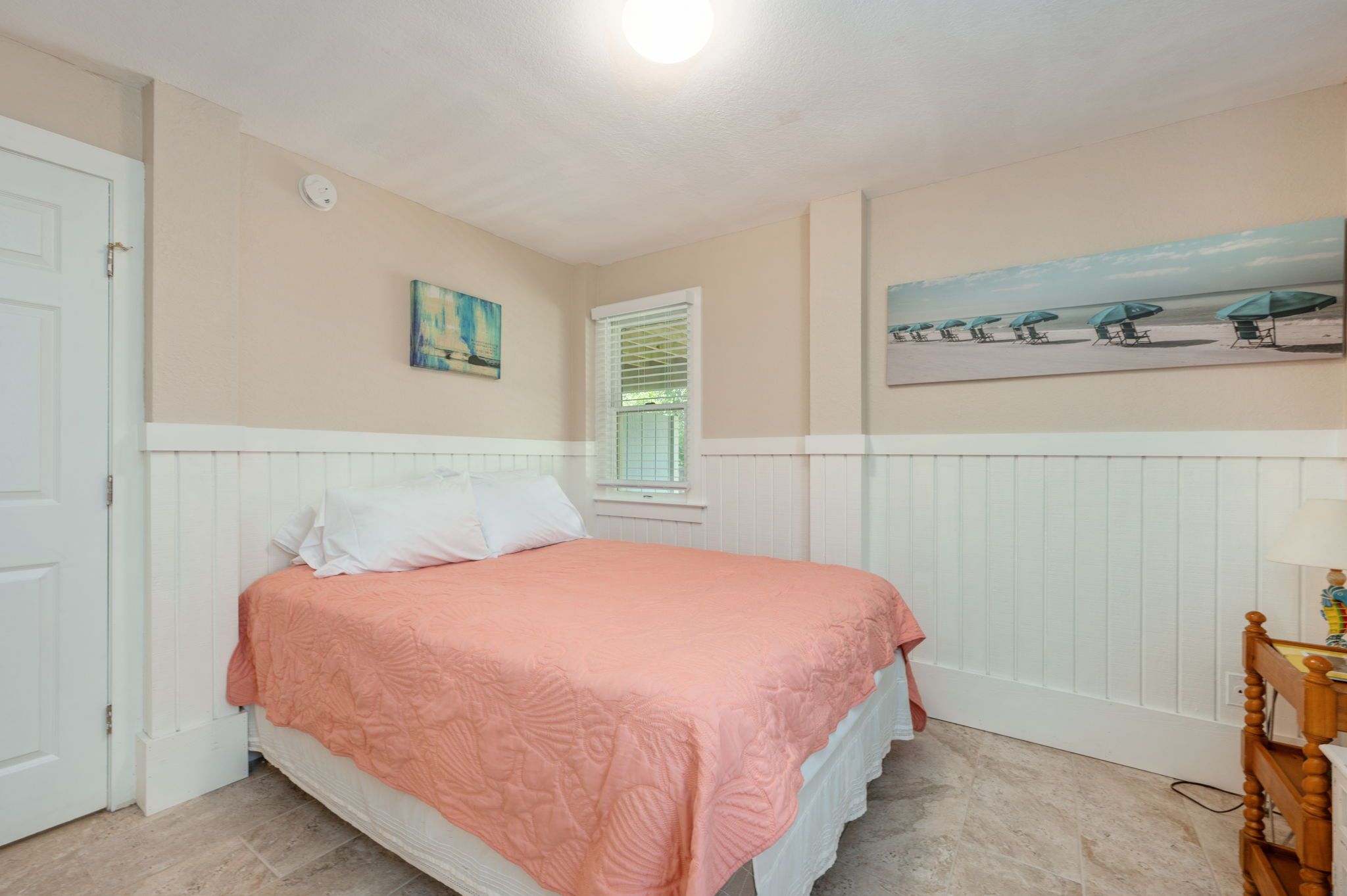 Een slaapkamer met een bed, een raam, een schilderij en een nachtkastje.