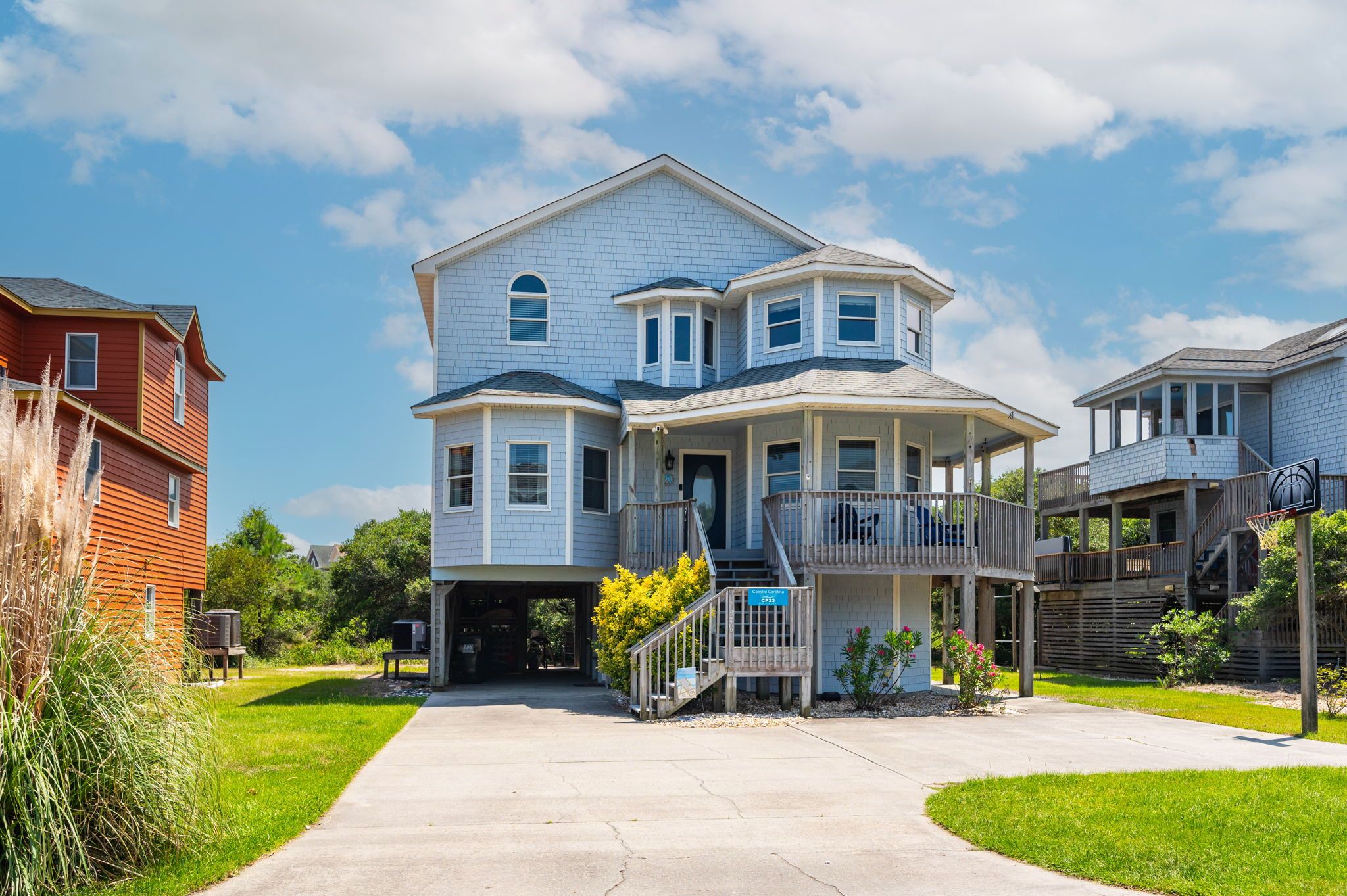 A two-story house with a front porch, a covered garage, and a basketball hoop in the backyard.