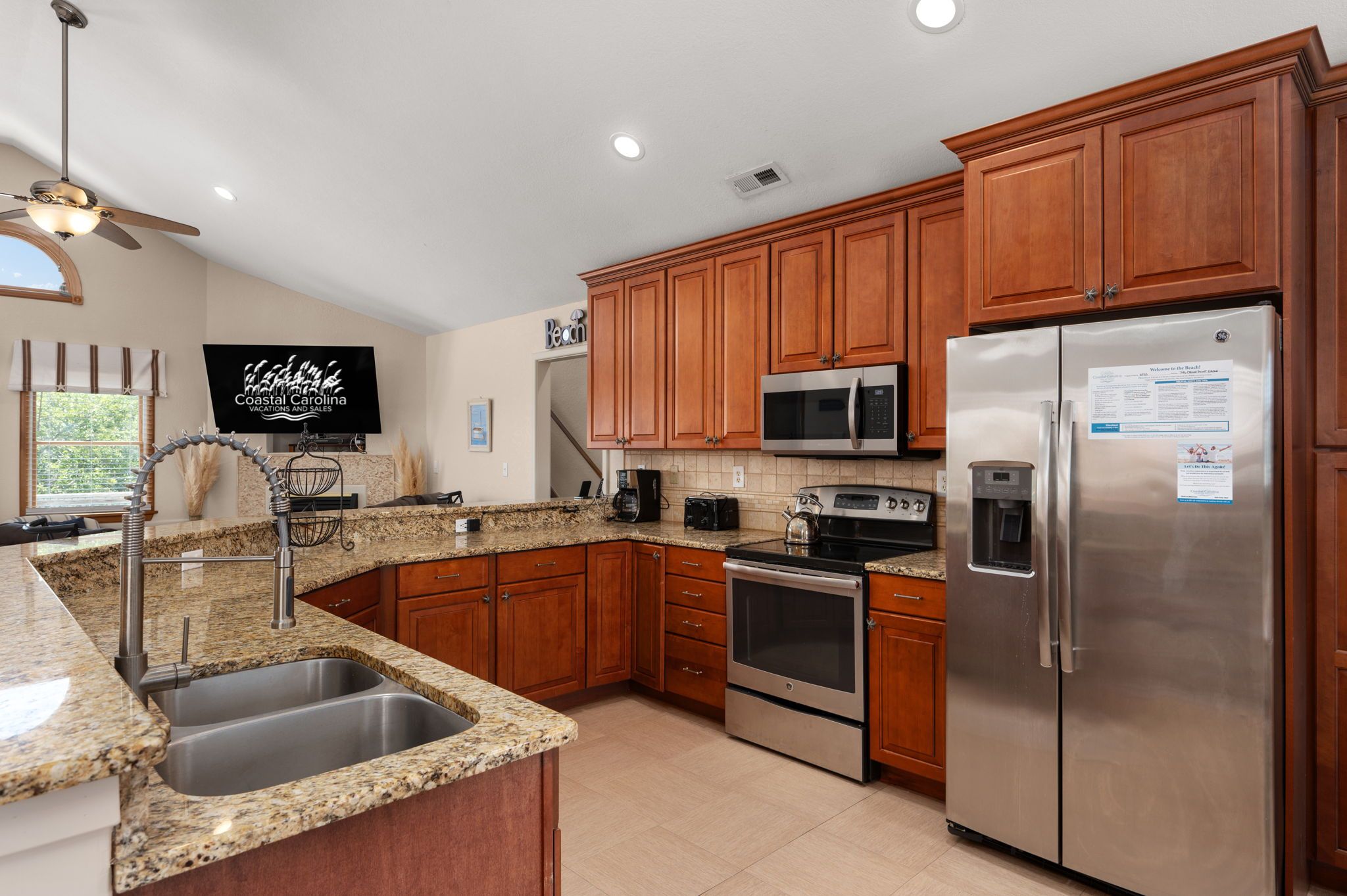 A modern kitchen with granite countertops, stainless steel appliances, wooden cabinets, and a built-in microwave.