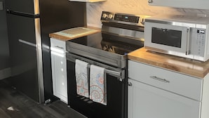 Una cocina moderna con electrodomésticos de acero inoxidable, armarios blancos y encimera de madera.