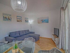 A modern living room with a sectional sofa, a glass coffee table with plants, a flat-screen TV, and nautical-themed wall art. - Wonderful private villa for 4 people with WIFI, A/C, private pool, TV, patio and pets allowed (Benissa)