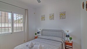 A bedroom with a bed, two bedside tables with lamps, a ceiling fan, and a window with curtains. - Wonderful private villa for 4 guests with A/C, WIFI, private pool, TV, patio and pets allowed (Benissa)