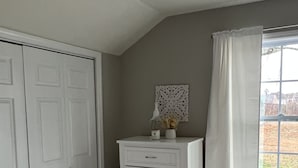 Een kamer met een witte ladekast, een decoratief wandobject en een raam met gordijnen.