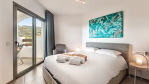 A modern hotel room with a large bed, a view through a sliding glass door, a painting on the wall, and a bedside table with a lamp. - Jardines - Tajaste 2.4 NATURE RESERVE VIEW 2B (Arona)