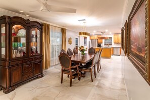 A dining room with a wooden dining table and chairs, a glass-fronted china cabinet, and a chandelier.