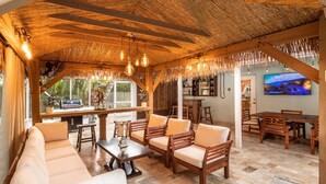 Un vaste espace extérieur aménagé avec du mobilier en bois et doté d’un toit de chaume.