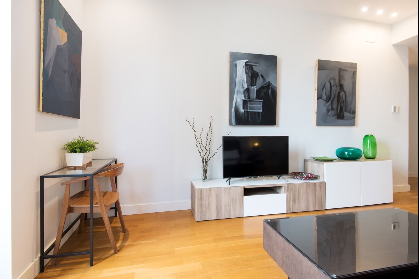A modern living room with a flat-screen TV, wooden furniture, and minimalist decor.