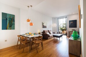 Una sala de estar moderna con comedor, piso de madera y decoración contemporánea.