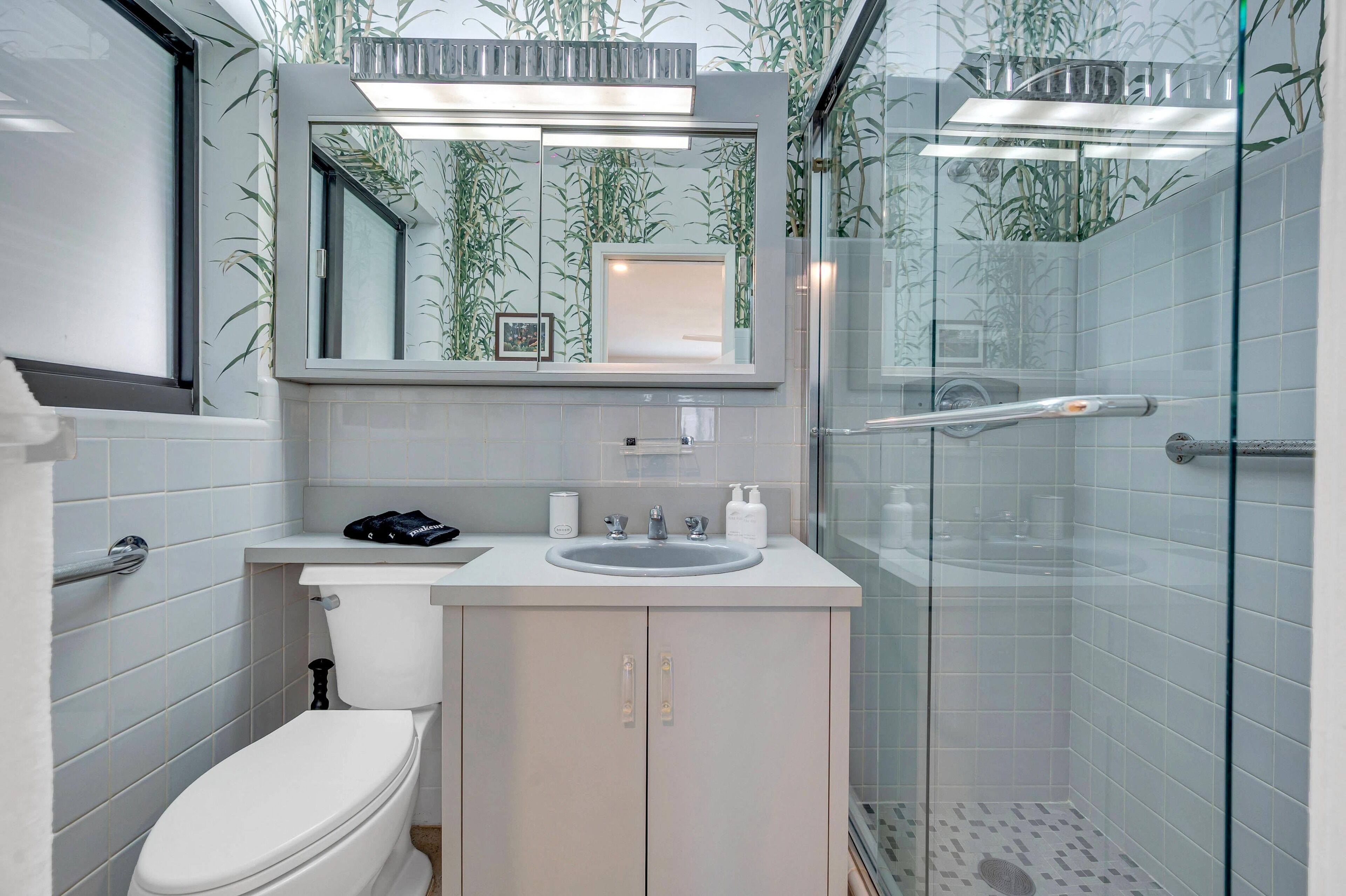 Een moderne badkamer met toilet, wastafel en douchecabine met glazen wanden.