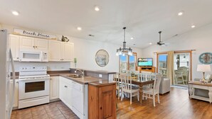 A spacious kitchen with white cabinets, a wooden island, and a dining area with white chairs. - 5180 Perfect Pastime * 5 Min Walk to Beach (Kill Devil Hills)