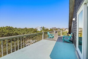 A balcony with a view of houses, a wooden railing, and two chairs.