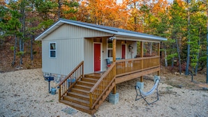 Une petite cabane avec une terrasse en bois, un porche et une allée gravillonnée.