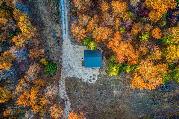 An aerial view of a house surrounded by colorful autumn foliage.