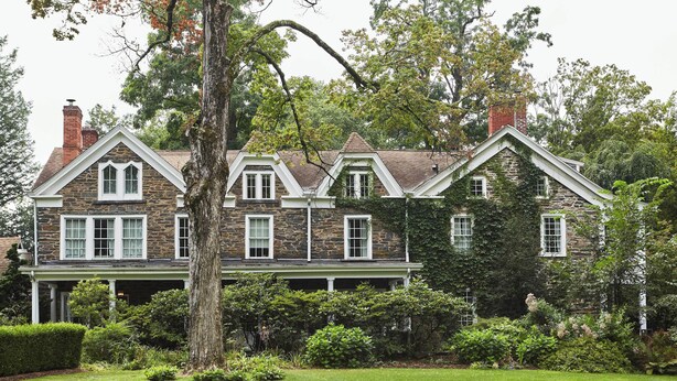 Une grande maison en pierre, dotée de nombreux toits à pignons et d’une cheminée imposante.