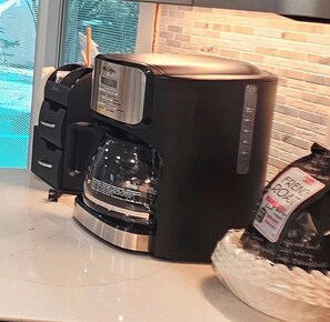 A coffee maker on a countertop with a bag of French Roast coffee.