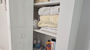 Une salle de bain avec une porte blanche, un porte-serviettes et une étagère contenant des articles de toilette.