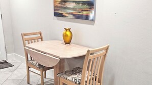Un coin repas avec une table et des chaises en bois, un vase doré et un tableau accroché au mur.