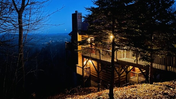 Eine Holzhütte mit einem Balkon mit Blick auf einen bewaldeten Bereich.