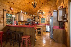 A wooden cabin interior with a kitchen, bar area, and seating.