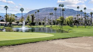 A golf course with a pond, palm trees, and mountains in the background. - Golf Course Condo. X-Large 2 Bedroom (Rancho Mirage)