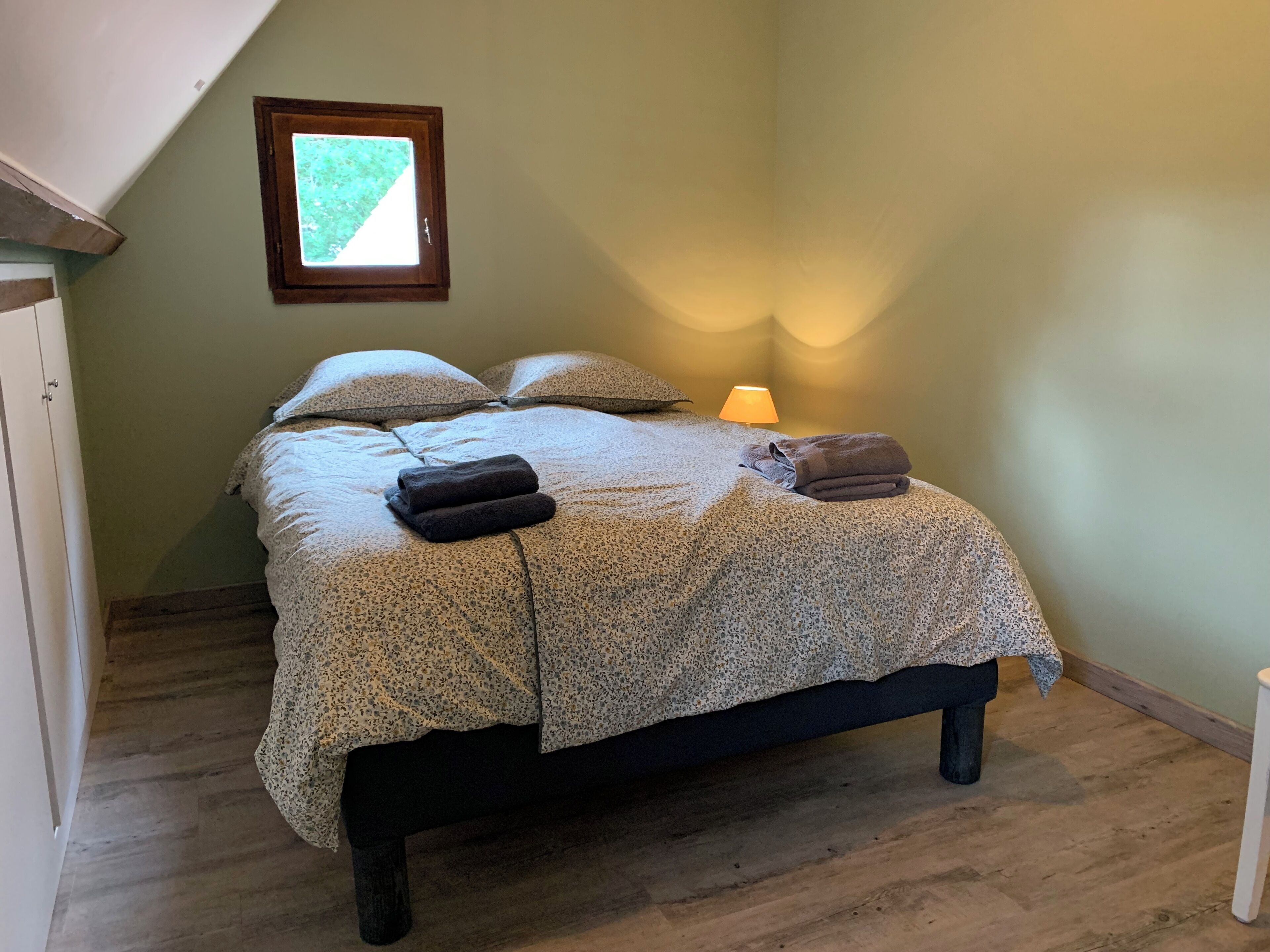 Une chambre à coucher avec un lit, des oreillers, une lampe et une fenêtre.