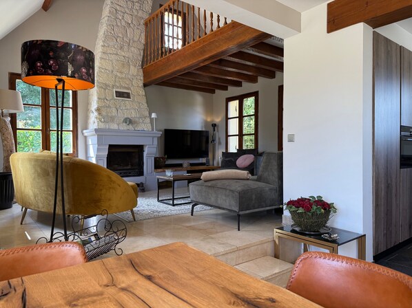 A cozy living room with a fireplace, a sofa, a TV, and a dining area.