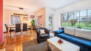 Un salon moderne avec un coin repas, de grandes fenêtres et une vue sur l’extérieur.