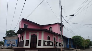 Ein zweistöckiges Haus in Rosa und Weiß mit einem Mittelbau, einer kleinen Veranda und einem Fahrrad vor der Tür.
