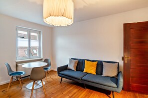 A room with a sofa, two chairs, a small table, a window with blinds, and a wooden door.