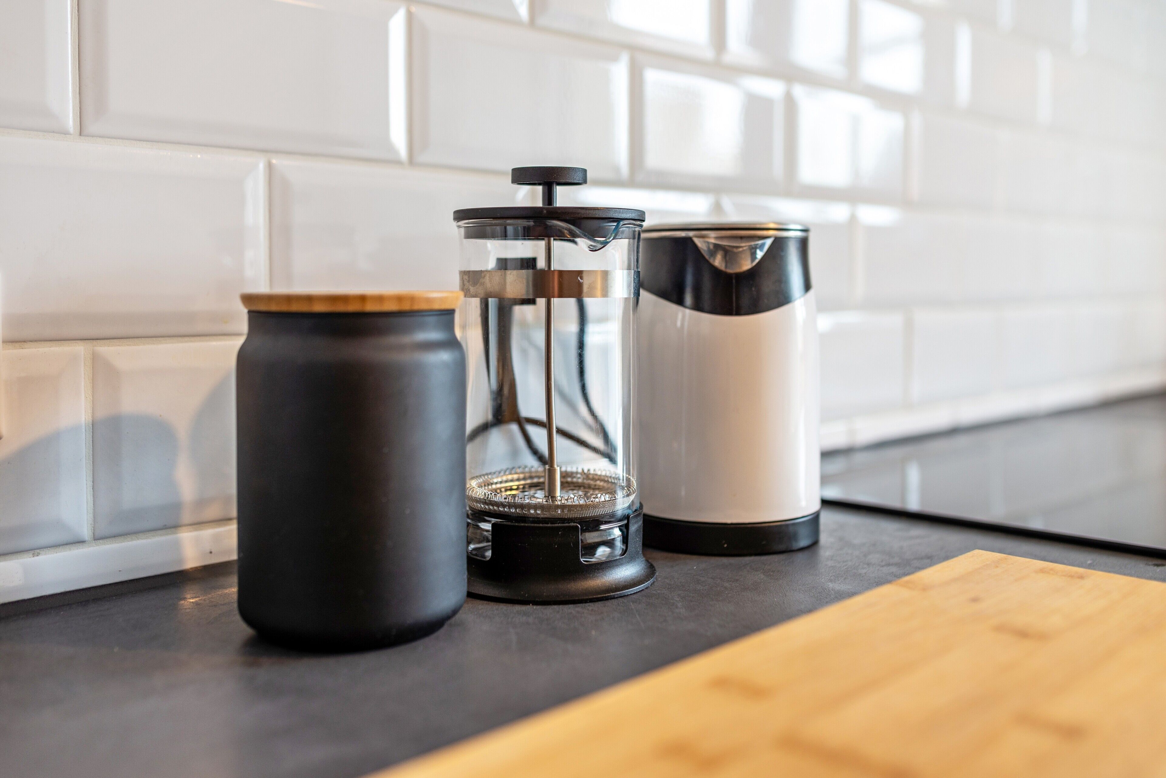 A kitchen counter with a coffee maker, a grinder, and a thermos.