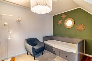 A bedroom with a bed, a chair, a floor lamp, and wall decorations.
