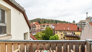 Un balcon avec une balustrade en bois, une petite table et un bol bleu.