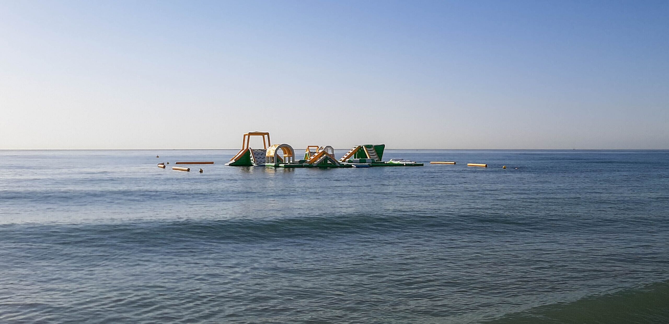 Une plage bordée d’une rangée de jeux colorés, aux couleurs verte et jaune.