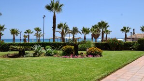 Ein gepflegter Garten mit Palmen, blühenden Pflanzen und freiem Blick auf das Meer.
