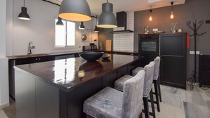 Una cucina moderna con una grande isola, sgabelli da bar, luci a sospensione e un frigorifero nero.