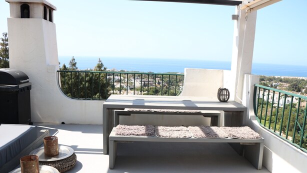 Un balcone con vista sul mare, dotato di barbecue e angolo relax con cuscini.