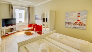 Ein Hotelzimmer mit einem Bett, einem Fernseher, einem roten Sessel und einem Gemälde eines Leuchtturms.