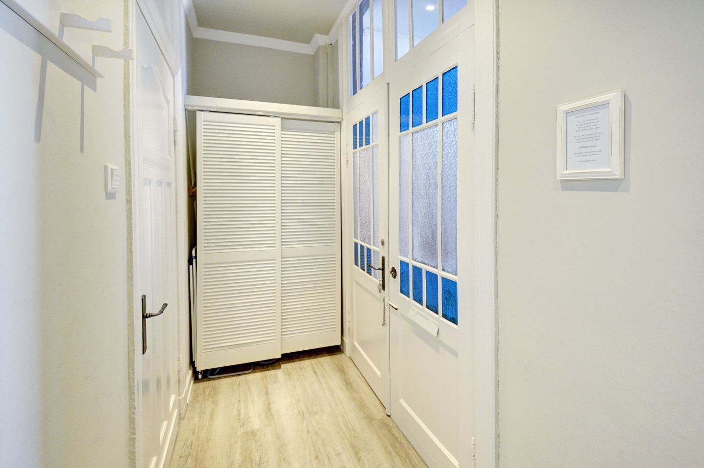Un couloir étroit doté d’une porte coulissante et d’une porte dont les panneaux sont en verre dépoli.