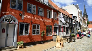 Ein rotes Gebäude mit der Aufschrift "BRAASCH-HOF WEIN & RUMHAUS BRAASCH" und einer weißen Flagge mit dem Text "Unss braa".