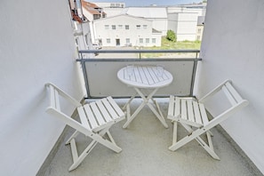 A balcony with two white folding chairs and a small round table.