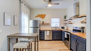 Una cucina moderna con pavimento in legno, frigorifero in acciaio inossidabile, forno a microonde e forno integrato.