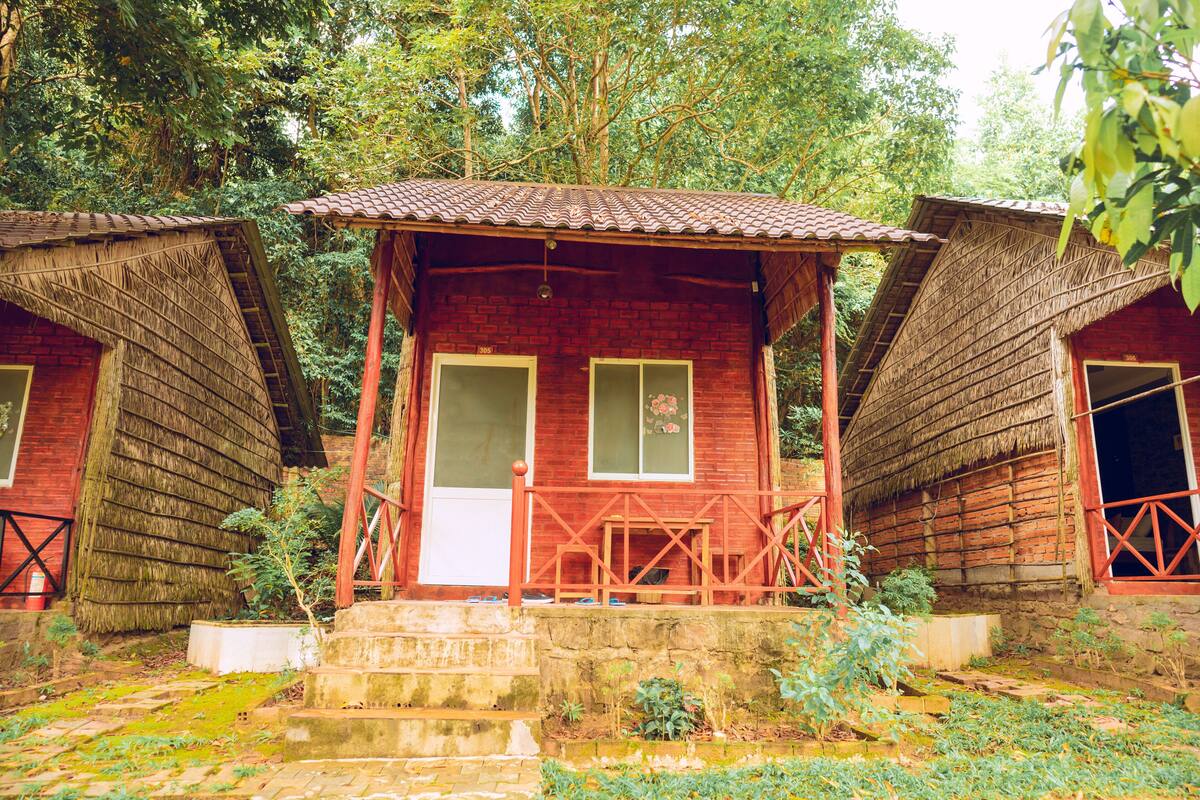 Une cabane en bois rustique, dotée d’un toit de chaume, d’un petit porche et d’une seule porte.