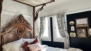 Un dormitorio con cama con dosel, dosel y ventana con cortinas.