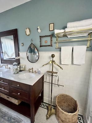 Un baño con dos lavamanos, un espejo, un perchero para toallas y un elegante soporte de latón decorativo.