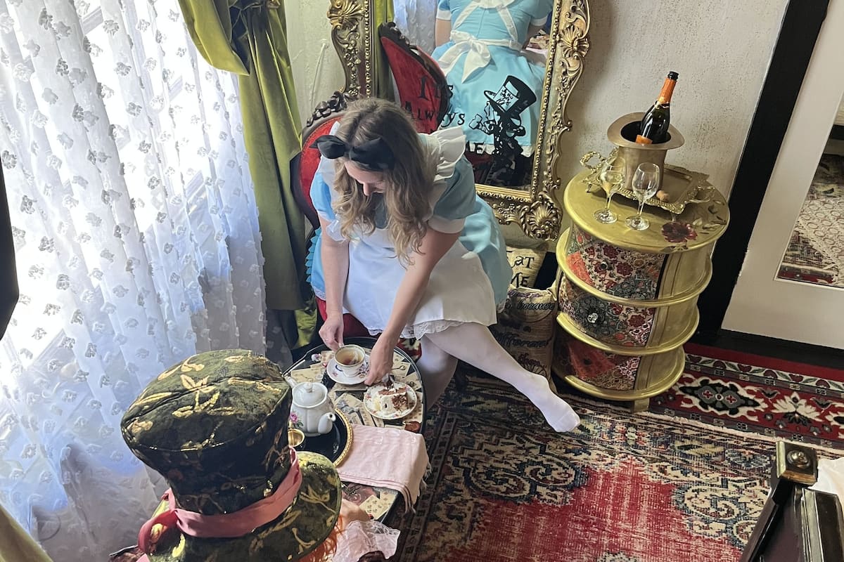 Una habitación con un espejo grande y ornamentado, una alfombra roja y una mesa dispuesta para tomar té.
