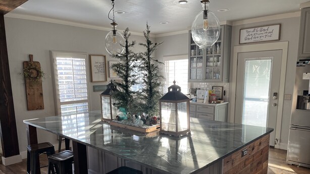 Cozinha moderna com ilha central, banquetas e uma árvore de Natal decorativa.